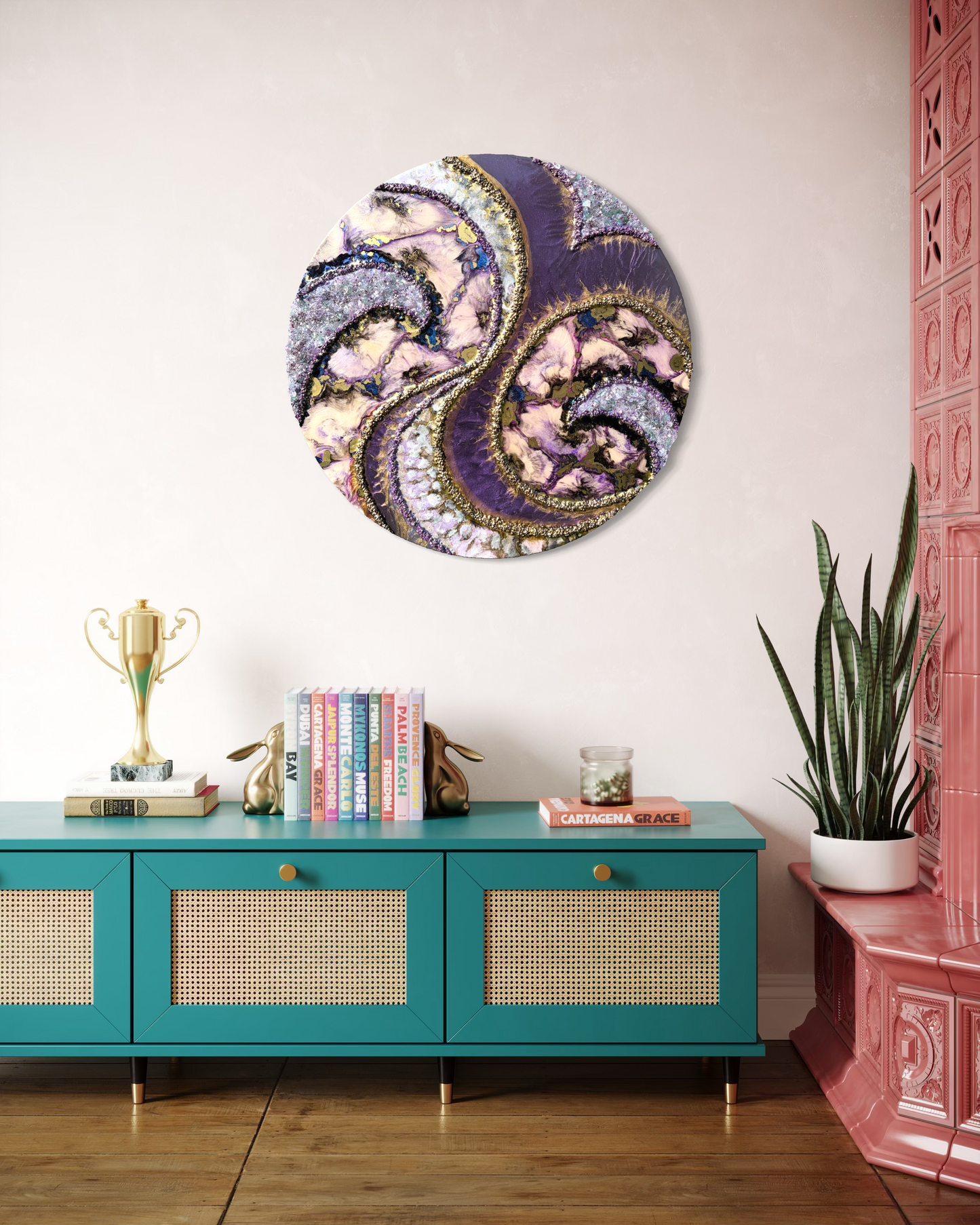 Decorative  maximalist style wall art on a wall above a teal console table with books and a plant.